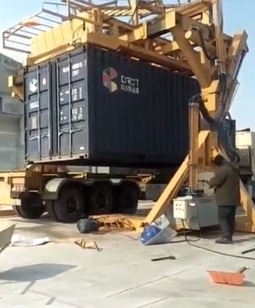 Workers are operating the container tilter for loading